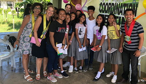 College officials pose for a photo with students and their teacher in the Philippines