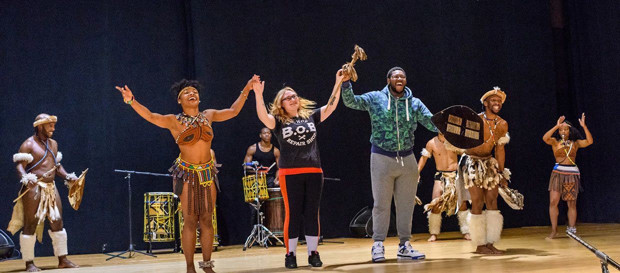 Students with performers from STEP AFRIKA on stage at an event on campus