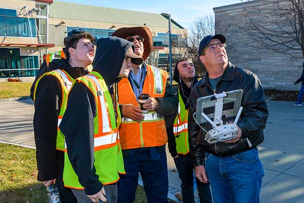Technology Lab Assistant Karl Hoegemann, right, a licensed drone pilot, works with Professor Bill Darling and some students in his surveying class.