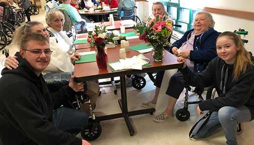 Students and residents at nursing center with flowers