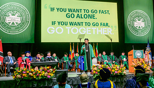 President Ramsammy on stage at installation ceremony with quote If you want to go fast, go alone. If you want to go far, go together. on screen behind him