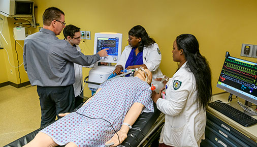 Respiratory care instructor and students working on patient simulator in lab setting