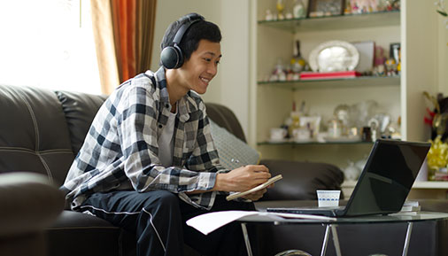 Male high school student studying at home on laptop
