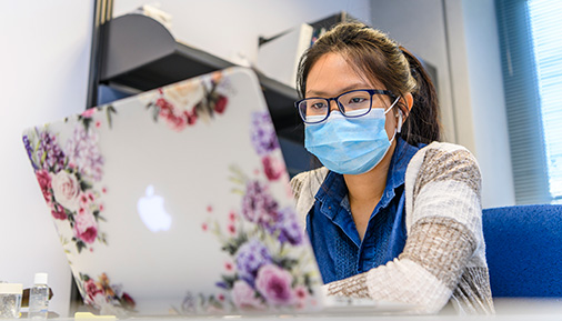 Female student with mask on laptop