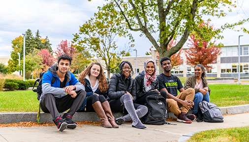 Students sitting on sidewalk on campus