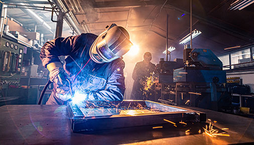 two handymen performing welding and grinding in the workshop