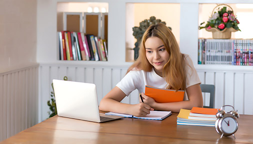 Young woman student working on laptop sitting at a desk